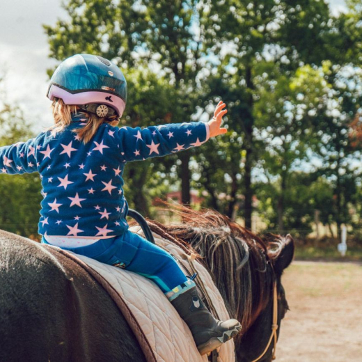 child horseback riding with arms outstretched